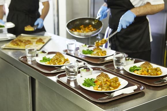  Kuchař umisťující ingredience z pánve na nádobí na podnosech