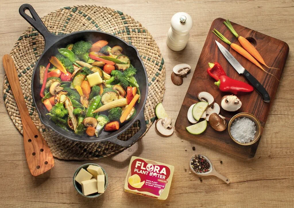 Kochbrett und Pfanne mit Gemüsegericht mit verschiedensten Gemüser und die Flora Butteralternative im 250g Format