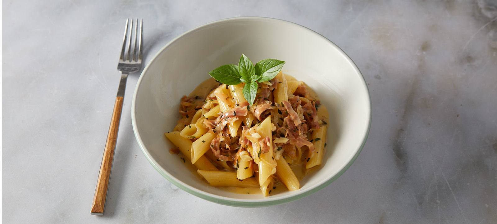 recipe image Πέννες a la cream με προσούτο και καραμελωμένα κρεμμύδια
