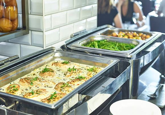 Melegen tartó pultok ételekkel svédasztalon