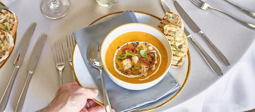 Kelner podający pomarańczową zupę do stołu 