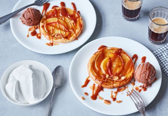 Dwa talerze z naleśnikami i lodami czekoladowymi wraz z dwoma kawami położone na stole