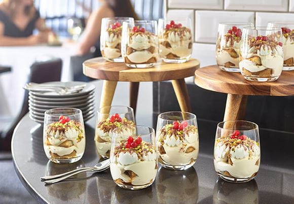  Porcje Panna Cotty podane w szklankach na blacie stołu restauracyjnego
