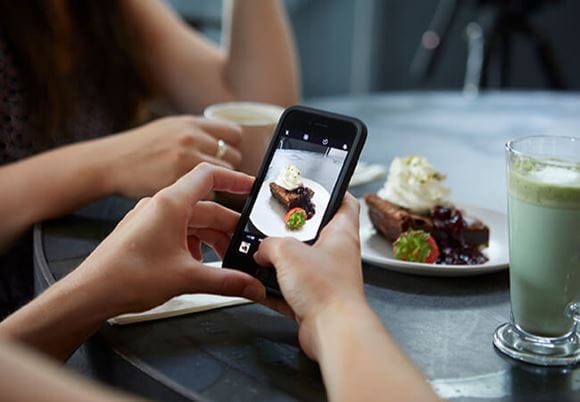 Osoba robiąca telefonem zdjęcie ciasta z bitą śmietaną