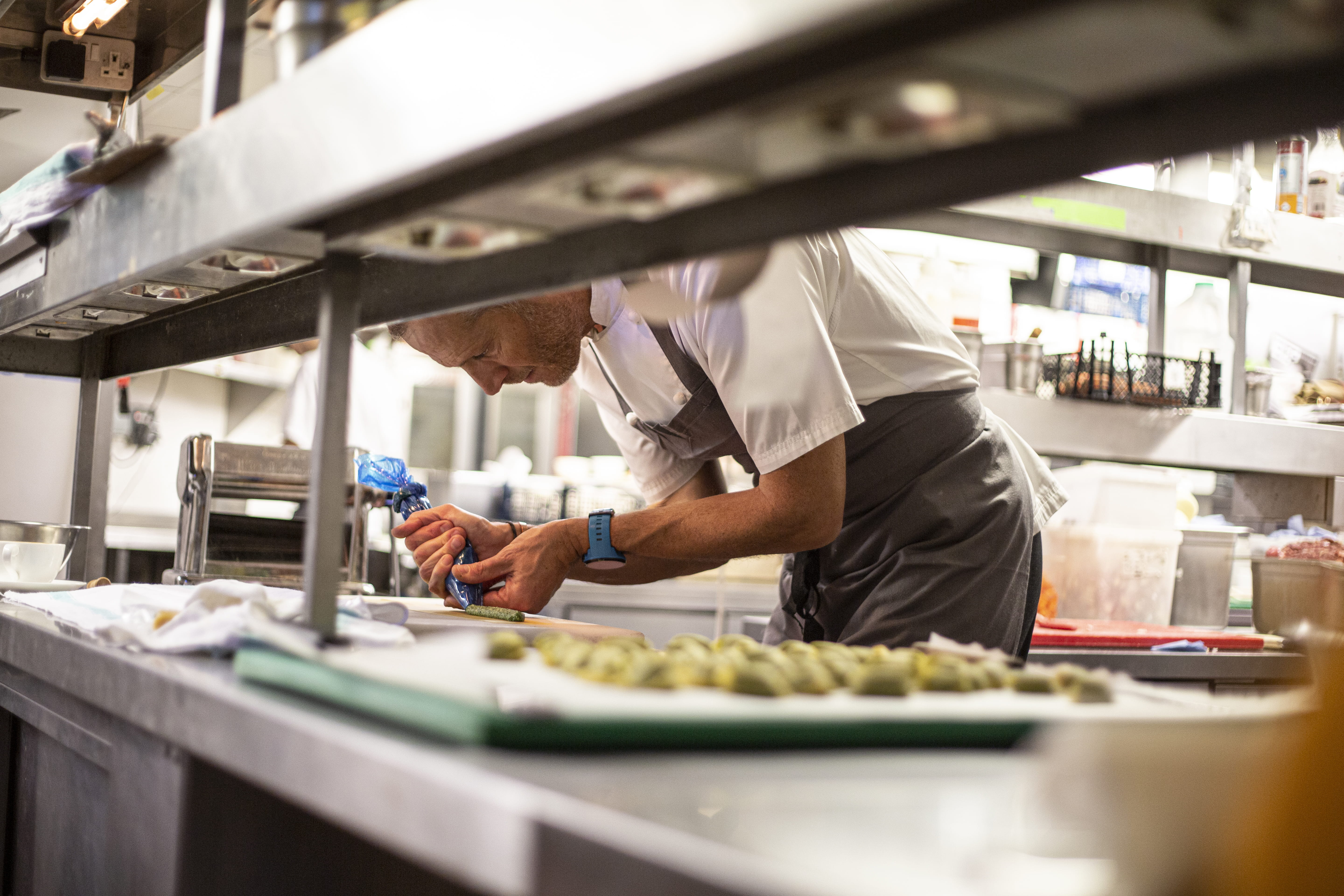 Cozinheiro a usar um saco pasteleiro para fazer sobremesas