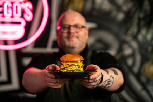 Kuchár drží tanier s hamburgerom